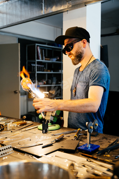 Glassblower Shaping Molten Glass for Wine Glass in Studio