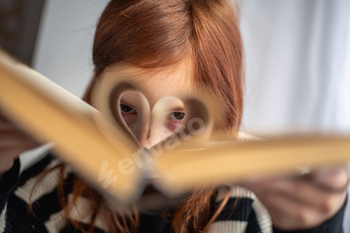 A girl is holding a book. Heart-shaped pages. Reading, Knowing, Learning