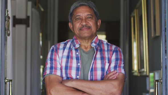 Senior mixed race man standing in open front doorway smiling