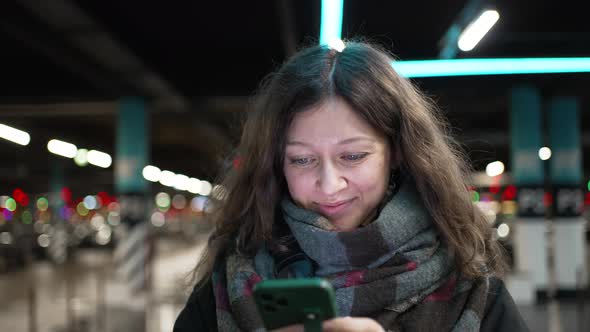 Woman Walks on Mall Parking Lot Looking at Phone Screen