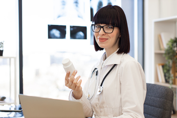 Confident female doctor holding medication bottle in medical office