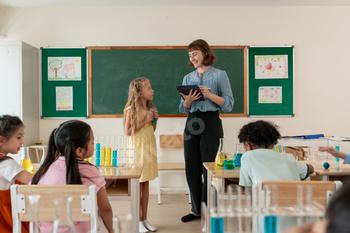 Adorable student learn with teacher in classroom at elementary school.