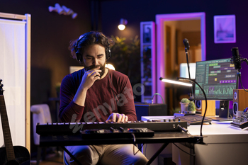 Male artist composing music on electronic piano keyboard