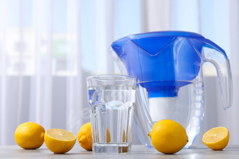 Water filter with fresh lemons and glass