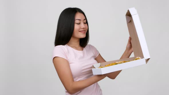 Asian Woman Opening Box And Showing Pizza Over White Background