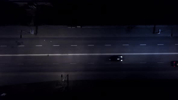 Aerial view road with cars in the night. Street lights. Raining. Cars passing by. Drone