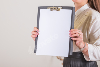 Woman holding clipboard with a blank sheet of paper. Blank paper poster in female hands. Blank