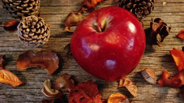 Apple and pine cone on wooden plank