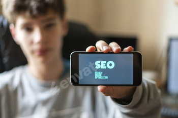 young male worker holding a smartphone with SEO text design in the office, search engine