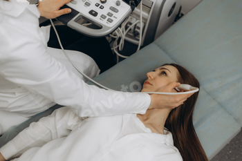 Doctor using ultrasound scanning machine for examining a head of woman