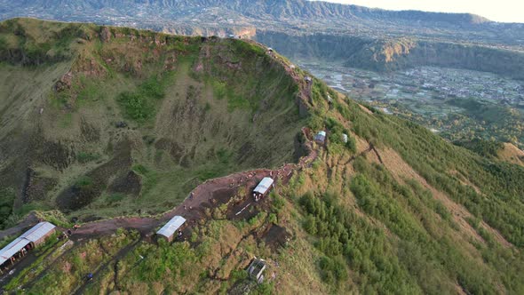 tourists walking the ridge along the crater rim of Mount Batur volcano during sunrise in Bali Indone