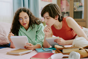 Studying Together on Bed with Notebooks and Gadgets