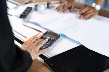 Engineer Working on Blueprints and Calculations with Calculator and Technical Tools on Desk