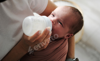 mother feeding her newborn baby formula from a bottle