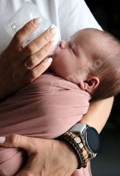 mother feeding her newborn baby formula from a bottle