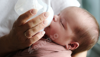 mother feeding her newborn baby formula from a bottle