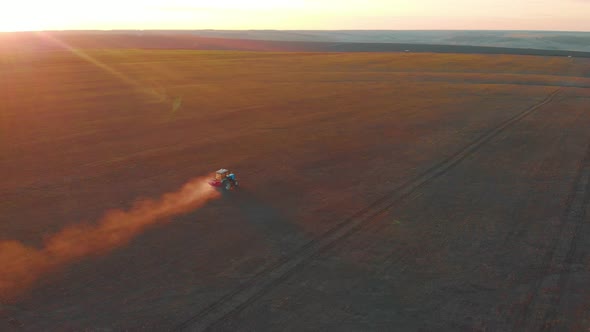 Tractor Spreading Artificial Fertilizers in Green Field