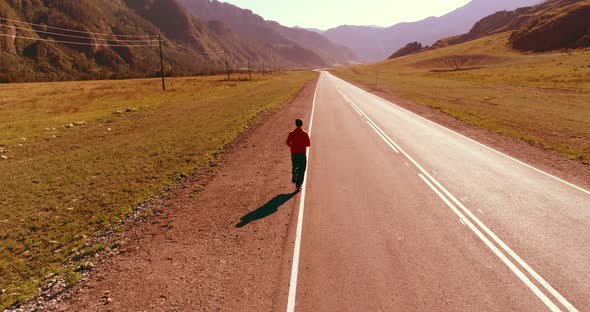 Low Altitude Flight in Front of Sporty Man at Perfect Asphalt Road