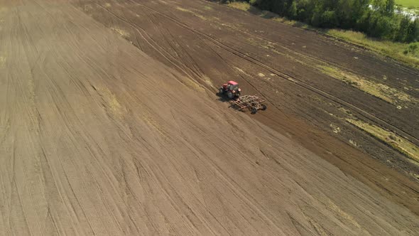 Farmer in a Modern Tractor Plows the Fertile Soil with a Chisel Cultivator in the Sunny Steppe