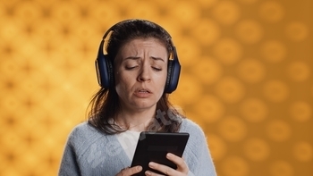 Voice actor frowns while reading ebook, portraying character, studio background