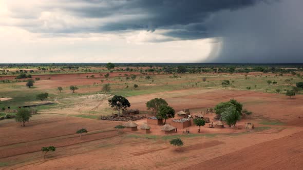 A traditional African village with heavy storm clouds rolling in rural Zambia, Africa. 4K