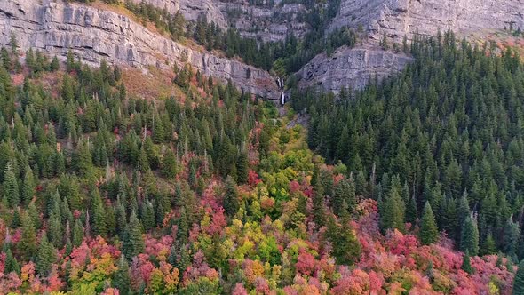 Flying over colorful trees towards rocky cliffs and Upper Falls in Provo Canyon