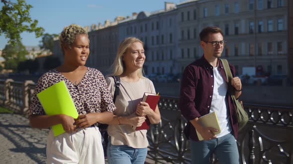 Group of Students Walking Together Along River Embankment and Talking