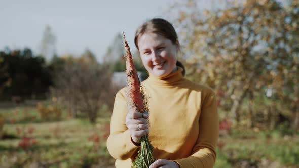 Woman Holds in Hands Fresh Carrot with Roots