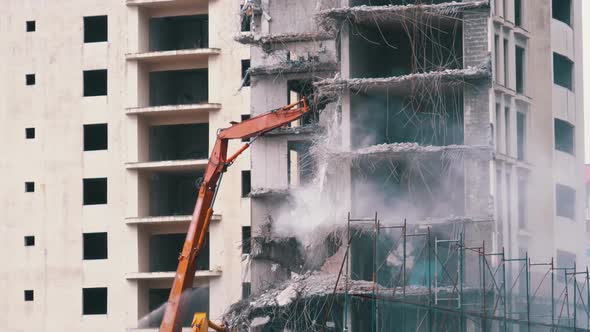 Destroying Old Concrete House Using Mechanical Arm of Bulldozer on Construction Site