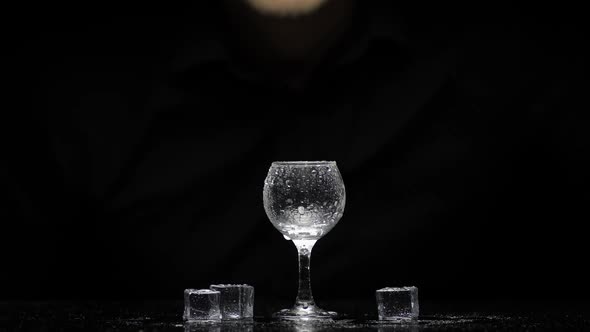 Barman Pour Frozen Vodka From a Bottle Into a Glass with Ice. Black Background