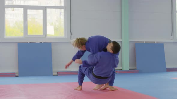 Male Ju-Jitsu Athlete Throwing Female Opponent during Fight