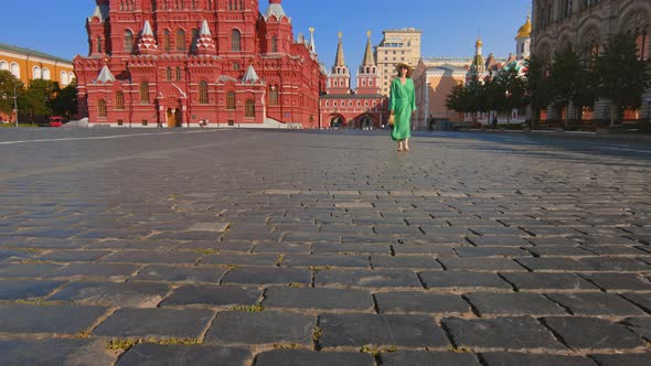 Beautiful girl in a green dress on an empty Red square