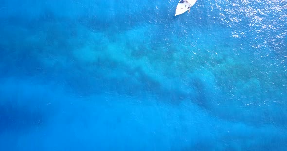 Natural drone travel shot of a white sandy paradise beach and aqua blue water background