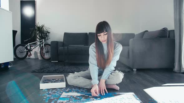 Young woman sitting cross legged assembling puzzle in her leisure time, trendy caucasian girl Jigsaw