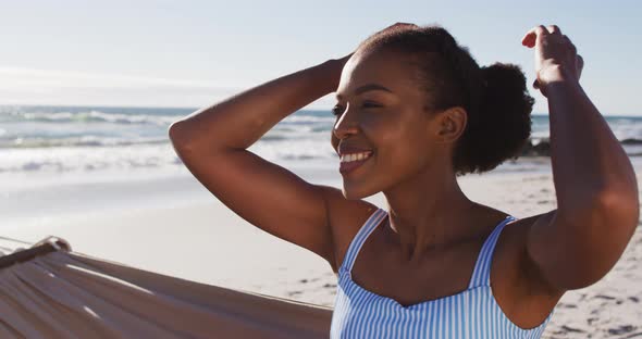 Close up of african american woman smiling while sitting on a hammock at the beach