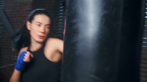 Active Brunette Sportswoman Fighting Punching Bag at Loft Background Medium Closeup