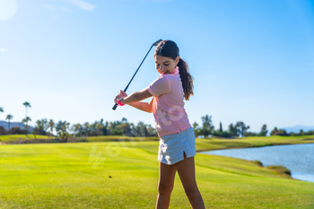 Girl learning how to swing golf in a course