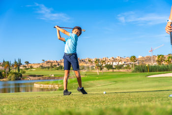 Young golfer swinging golf in a course