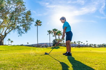 Boy playing golf in a green course