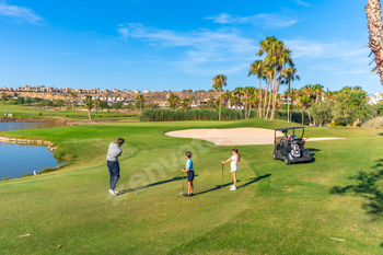 Instructor teaching golf to two children in a course