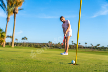 Young female golfer putting on golf course