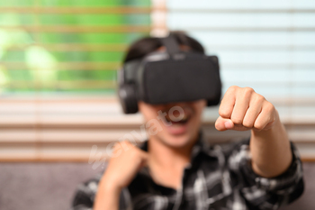 Joyful young man playing boxing game on virtual reality headset at home