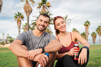 A fit couple catching their breath while sitting on the grass after a sprint session of cardio