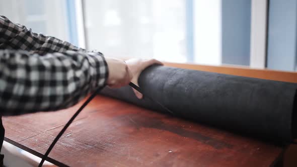 The Man in the Workshop of the Tanner Lays on the Table a Roll of Processed Animal Skin