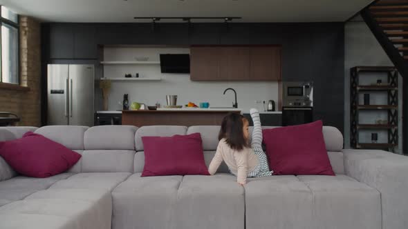 Cute Happy Asian Toddler Girl Crawling on Sofa at Home