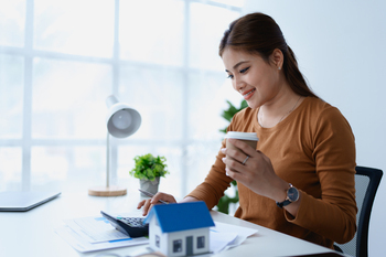 Woman Home Finance Management using calculator, computer and documents Mortgage to plan calculate