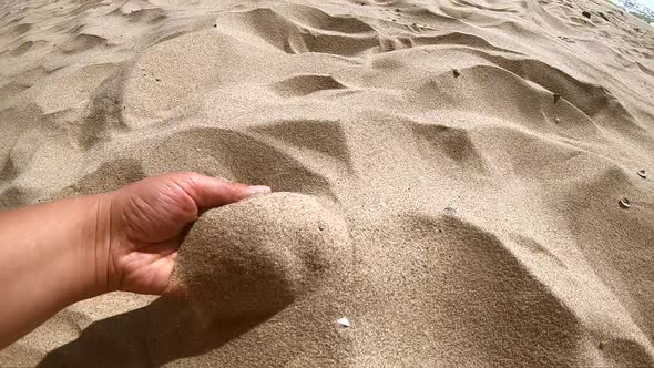 Girl Scoops Handful of Sand in Her Palm Scatters Sand Through Fingers