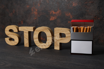 The word stop with a pack of cigarettes on a dark background