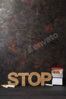 The word stop with a pack of cigarettes on a dark background