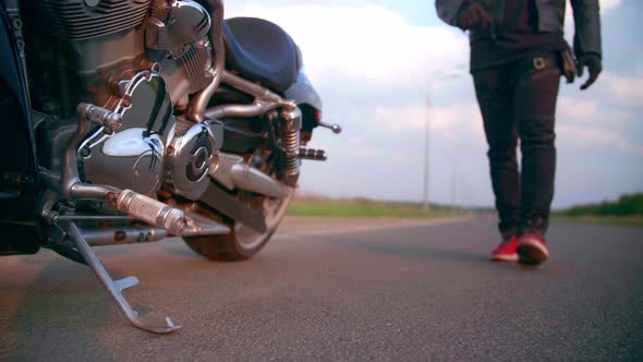 Motorcyclist Walks on the Road to His Motorcycle Chopper